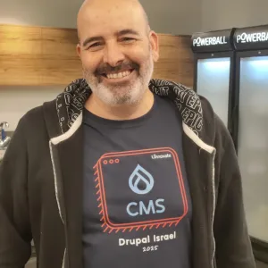 Smiling man in a CMS-themed t-shirt stands indoors with coolers in the background.
