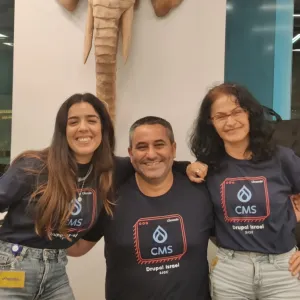 Three people smiling in front of an elephant wall sculpture.