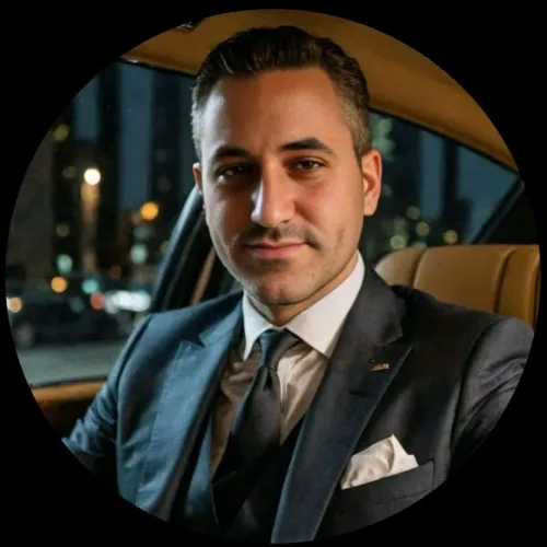 Man in a suit sitting in a car at night, city lights visible outside the window.