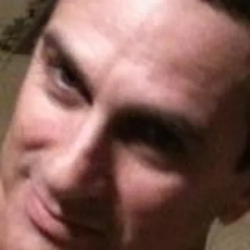 Man with short dark hair smiling slightly, close-up of face.