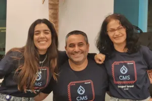 Three people smiling in front of an elephant wall sculpture.