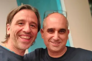 Two smiling men wearing matching navy blue t-shirts with a graphic design.
