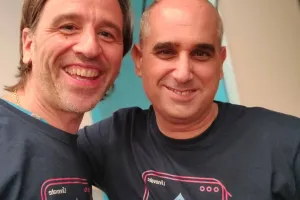 Two smiling men wearing matching navy blue t-shirts with a graphic design.