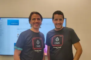 Two smiling men in navy blue Drupal CMS t-shirts stand in front Live Demo of Drupal.org.il